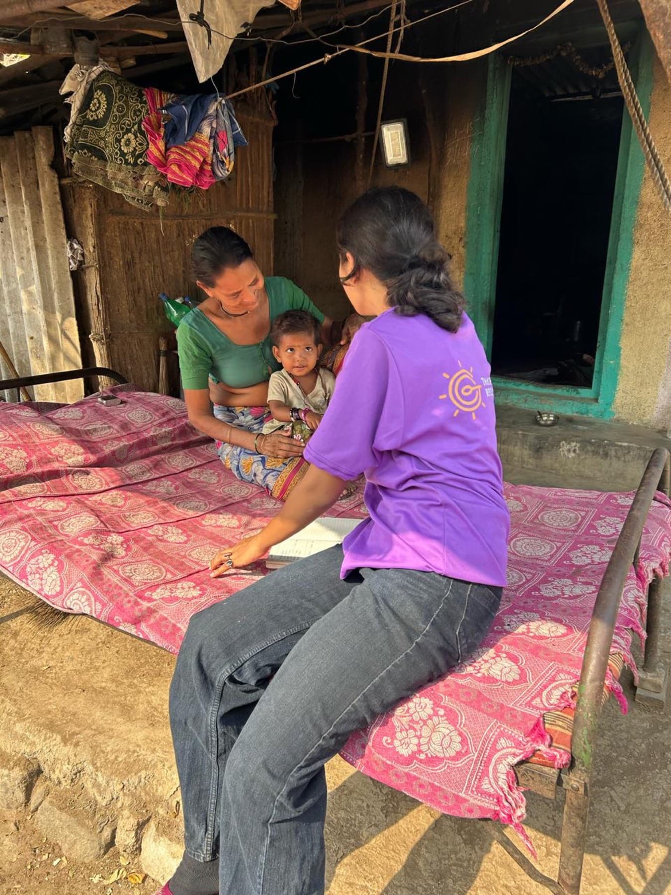 A field worker sits with a mother and her child during a home visit.